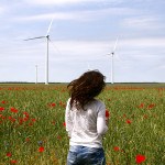 Femme de dos avec éolienne dans champ