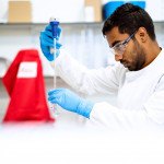 Ingénieur avec pipette, gants bleus, lunettes et tissus rouge